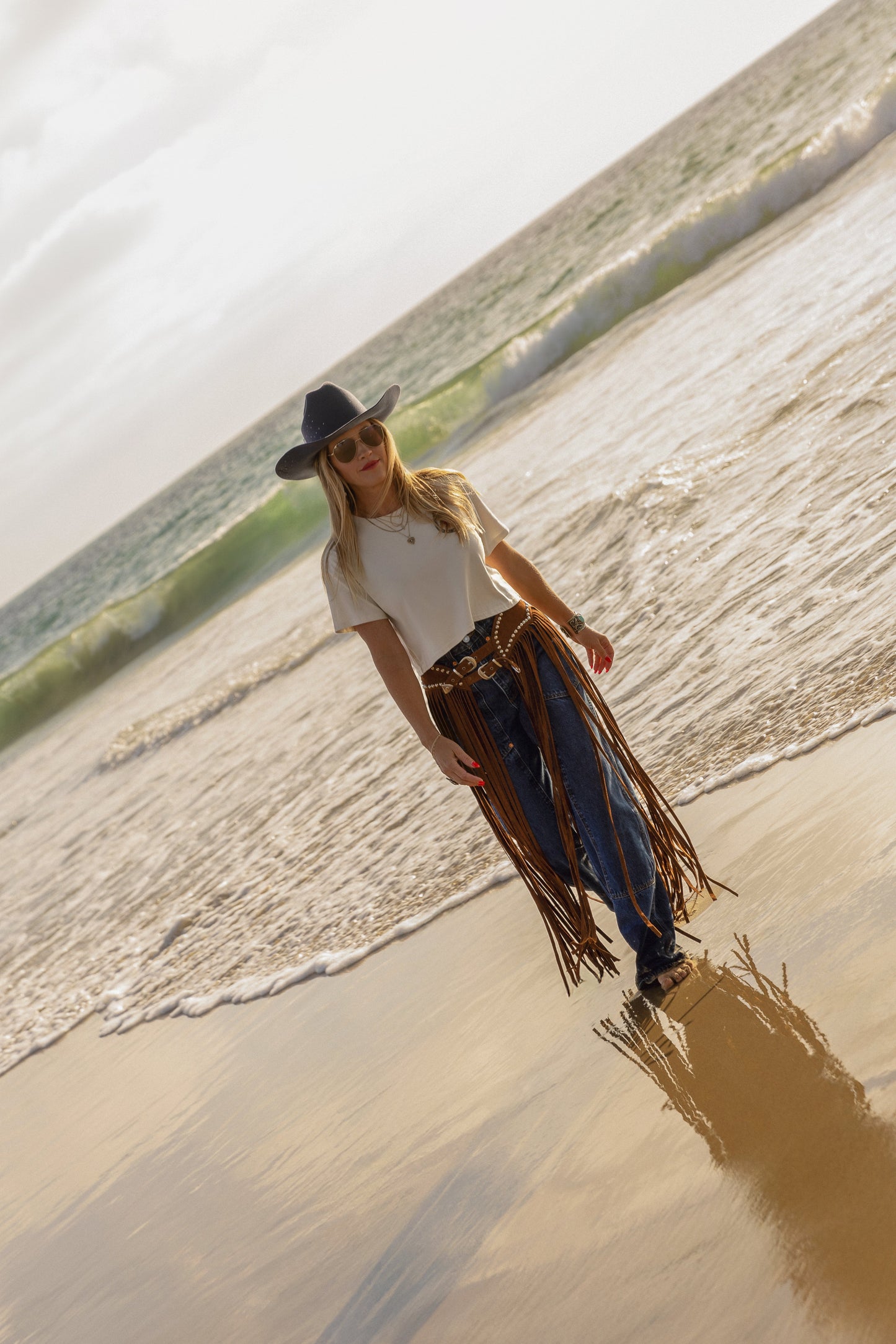 Person walking on a beach with a white shirt and dark pants