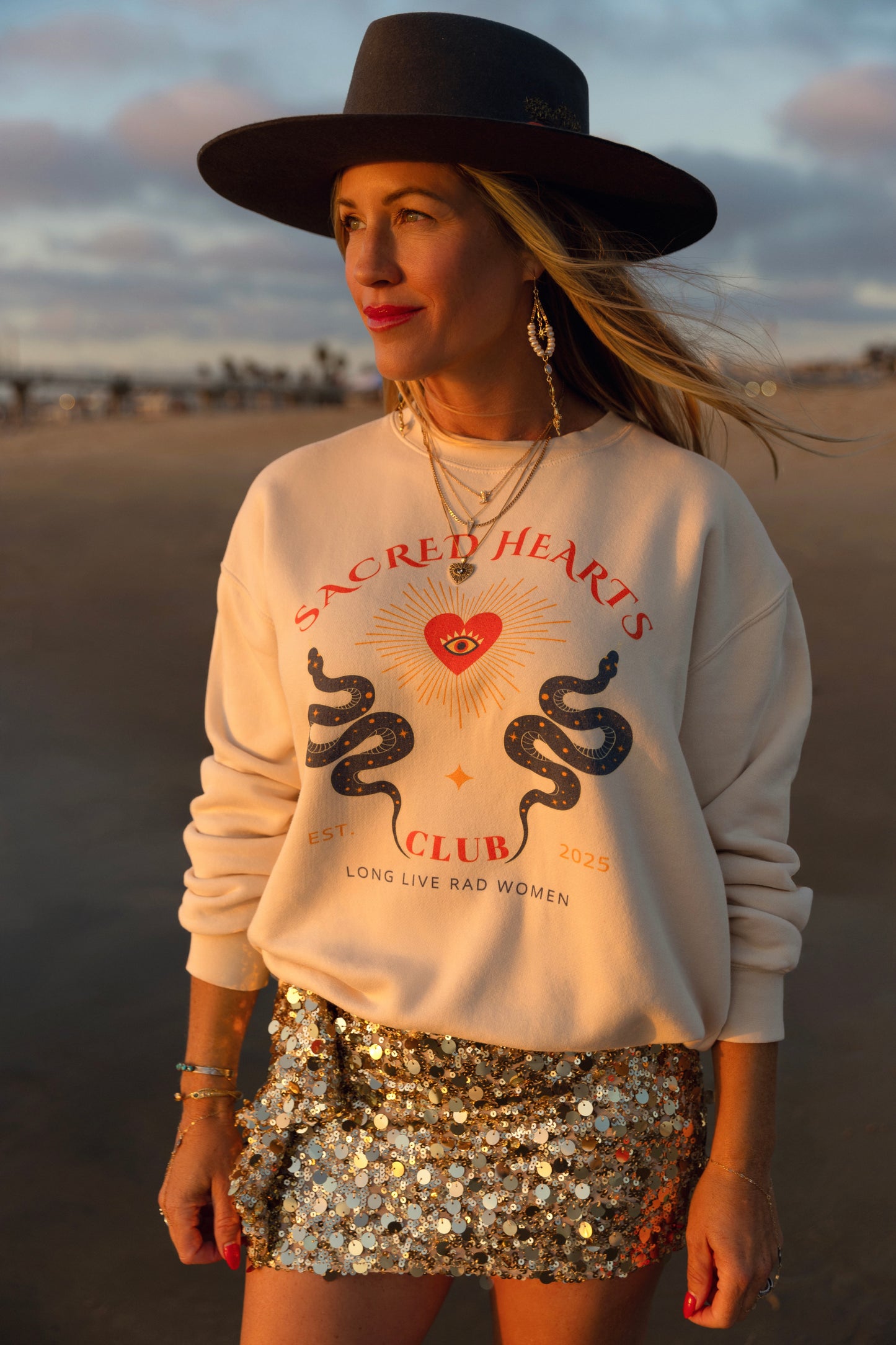 Woman wearing a sweatshirt with a graphic design and a sequin skirt in a desert setting